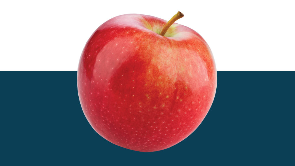 Bright red apple cut out on blue background.