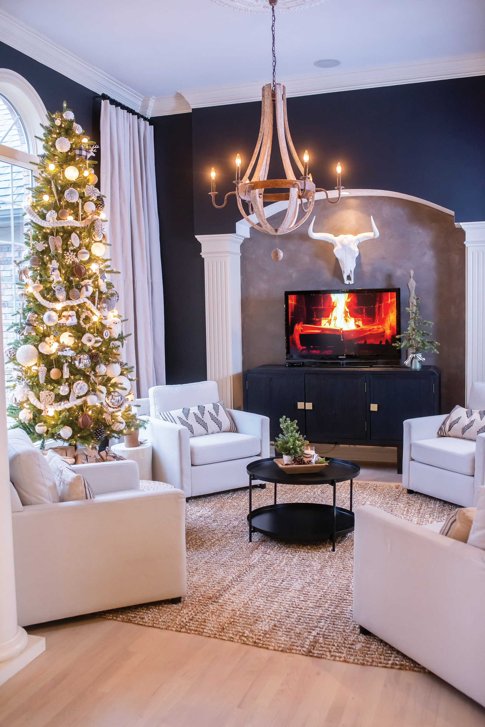 Bold and dramatic sitting room featuring a neutral Christmas tree wooden chandelier animal skull and yule log on TV