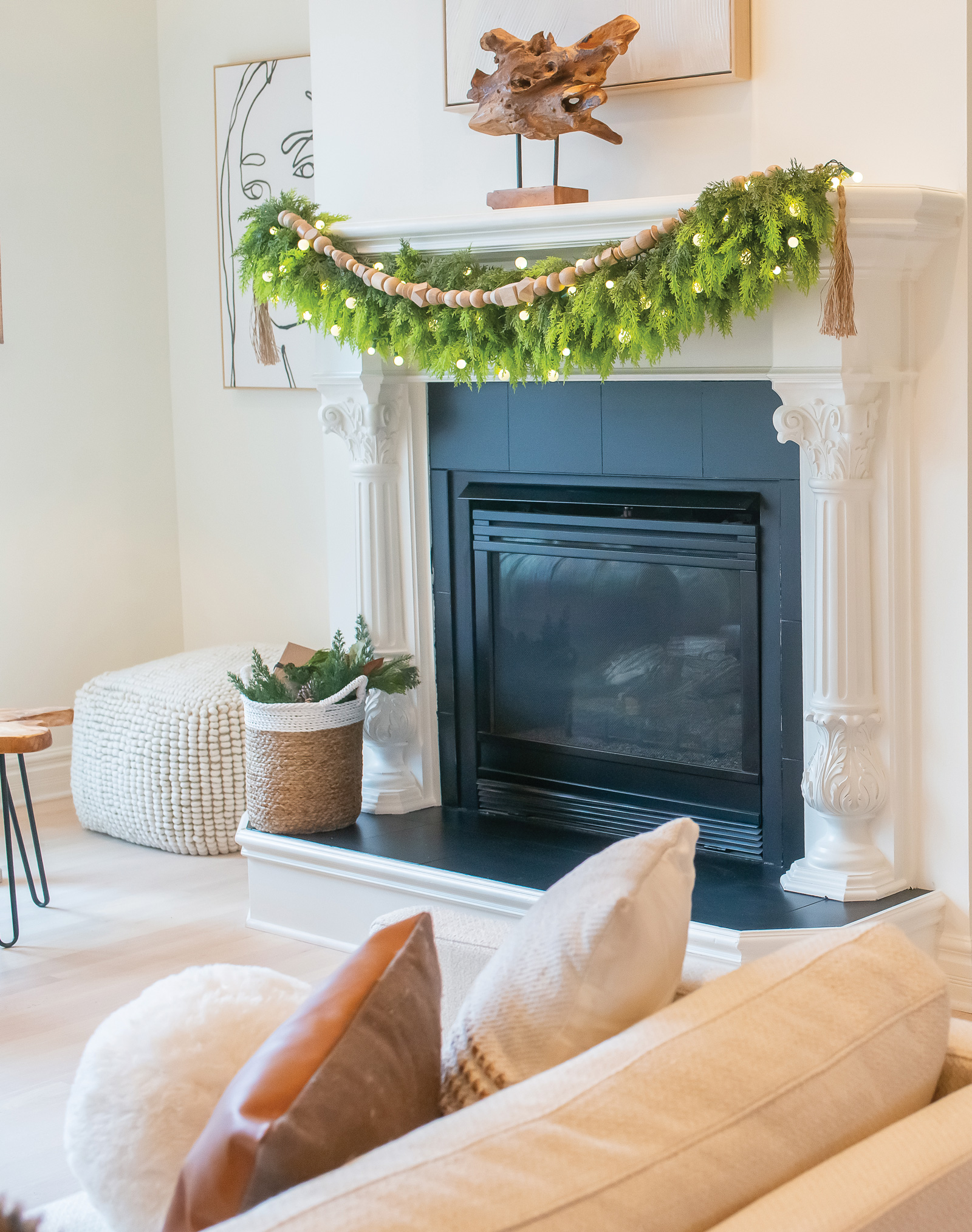 Fireplace mantle decorated with lush holiday greenery and minimalist wooden garland