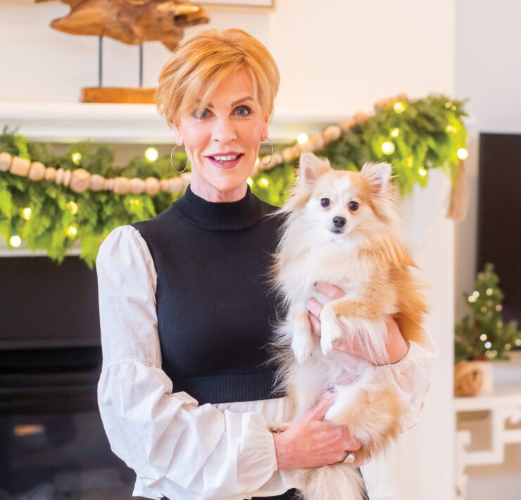 Interior designer Anne Tuckley poses with her dog in front of her fireplace