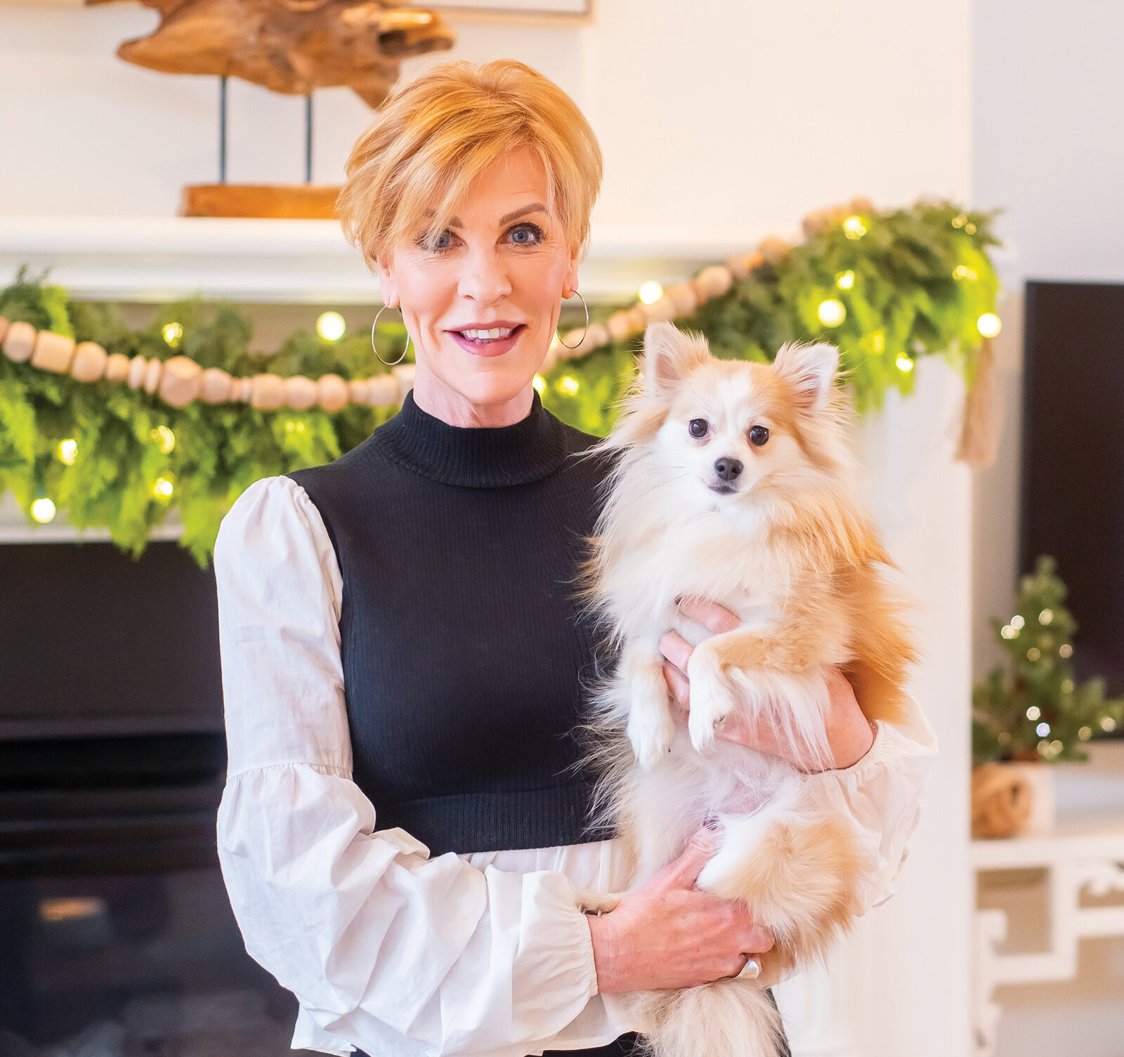 Interior designer Anne Tuckley poses with her dog in front of her fireplace