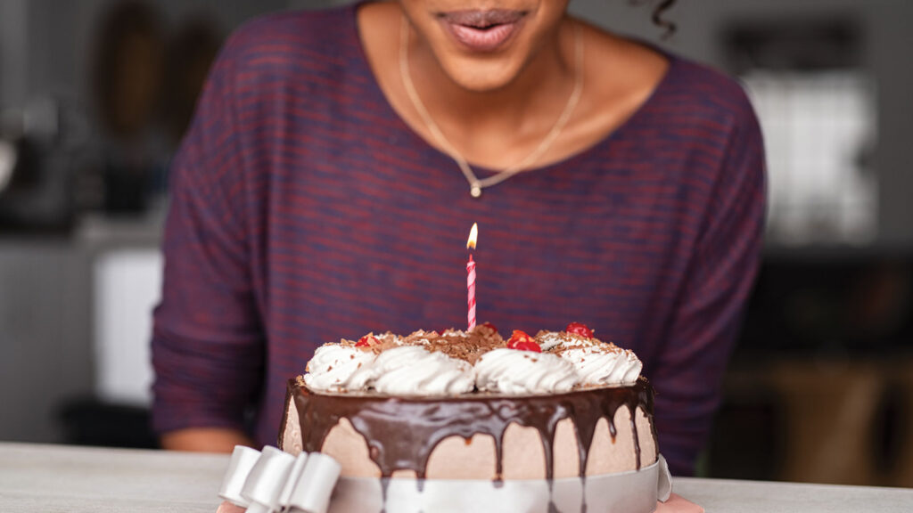 Woman blowing out candle on birthday cake