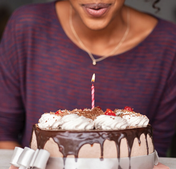 Woman blowing out candle on birthday cake