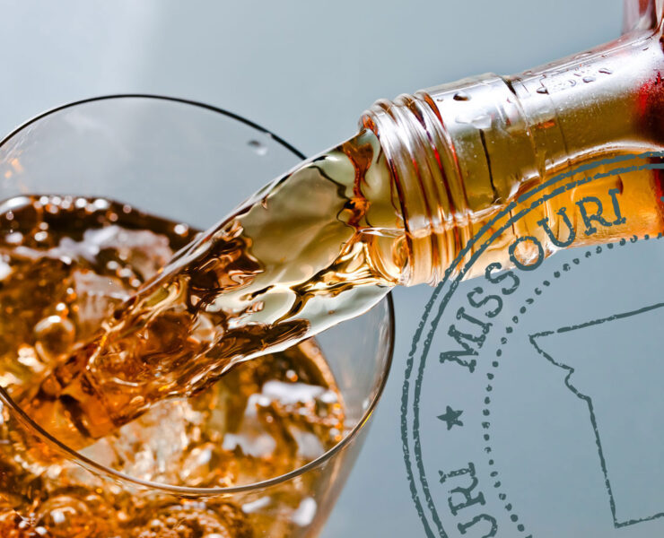 Glass with whiskey and ice on a glass table with a Missouri badge