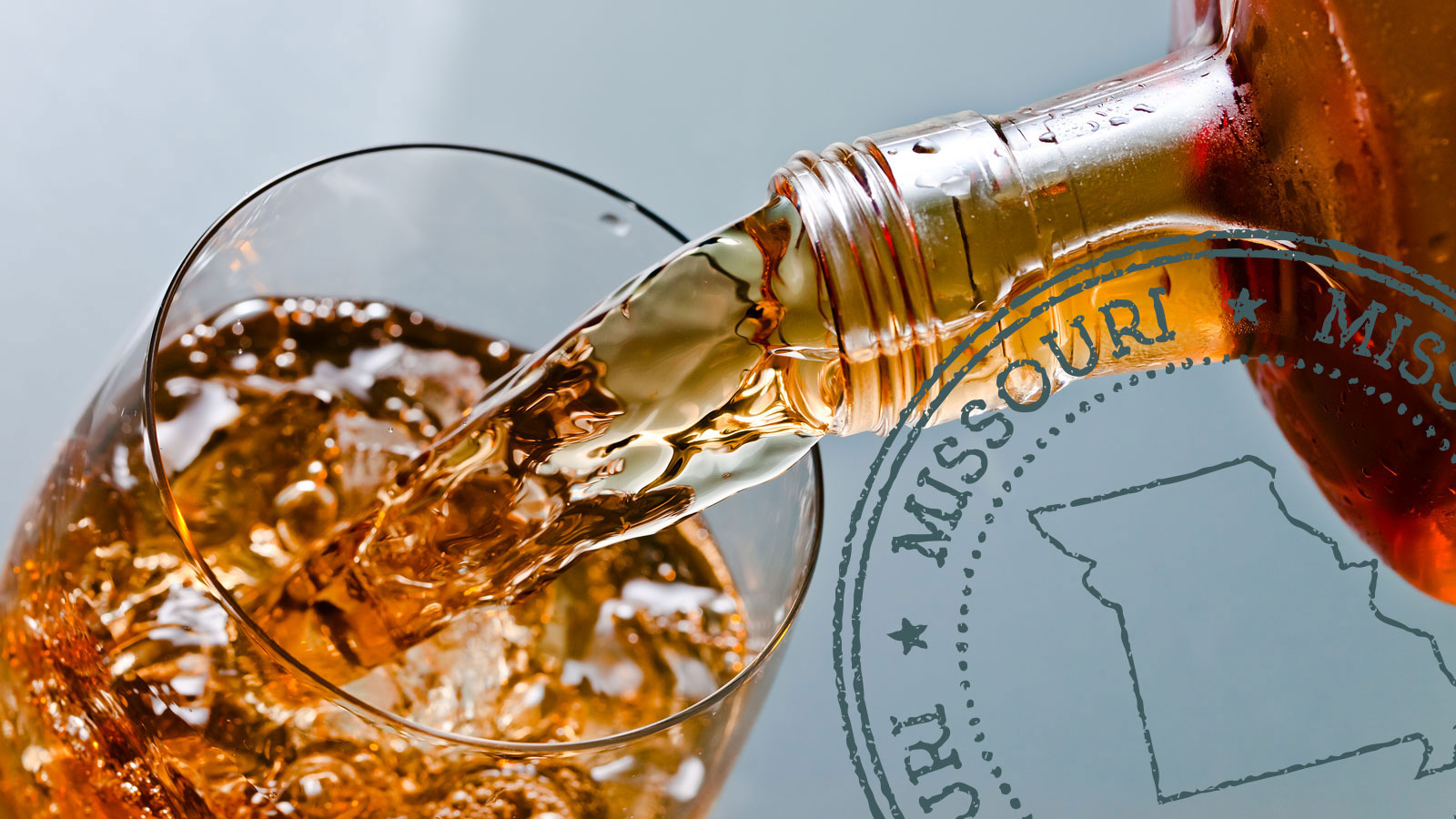 Glass with whiskey and ice on a glass table with a Missouri badge