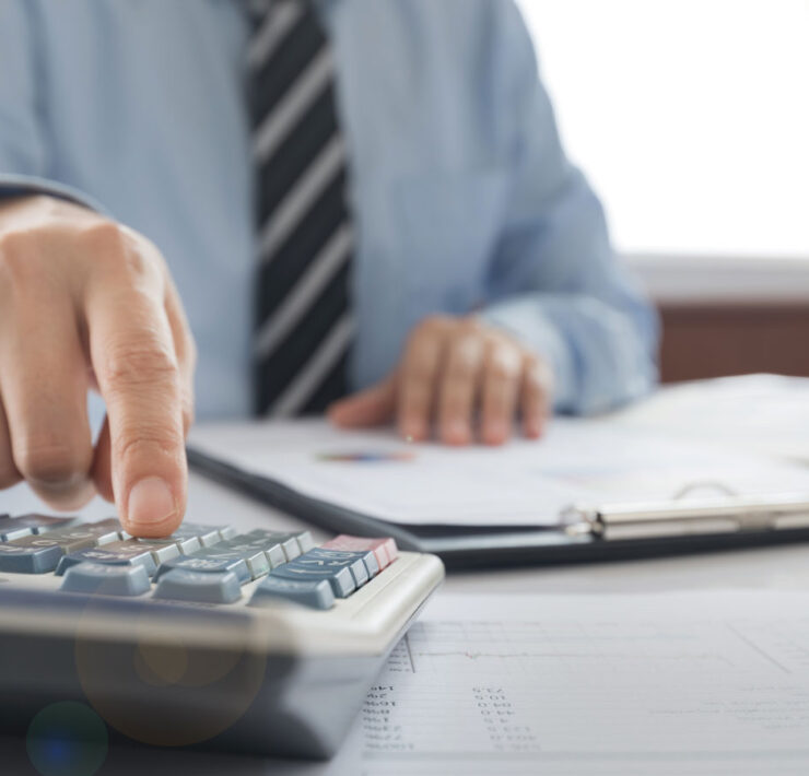 Man in tie working with a calculator and financial documents