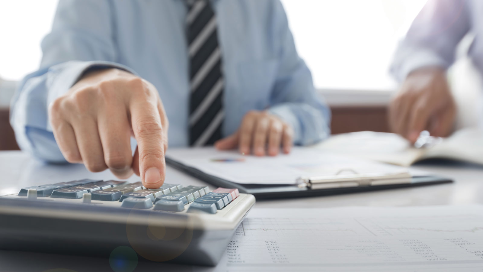 Man in tie working with a calculator and financial documents