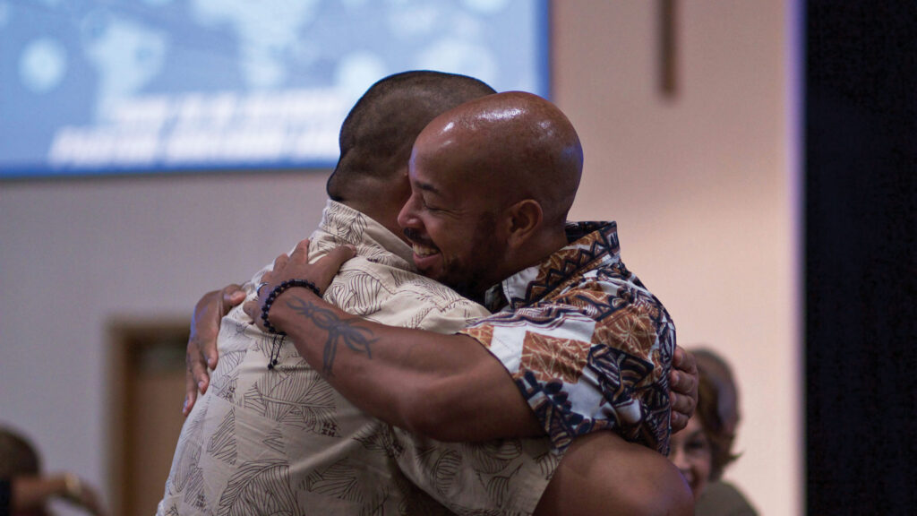 Two men smiling and embracing during worship