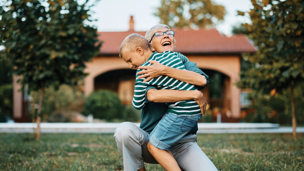 Older woman hugging young child in a yard