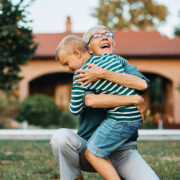 Older woman hugging young child in a yard