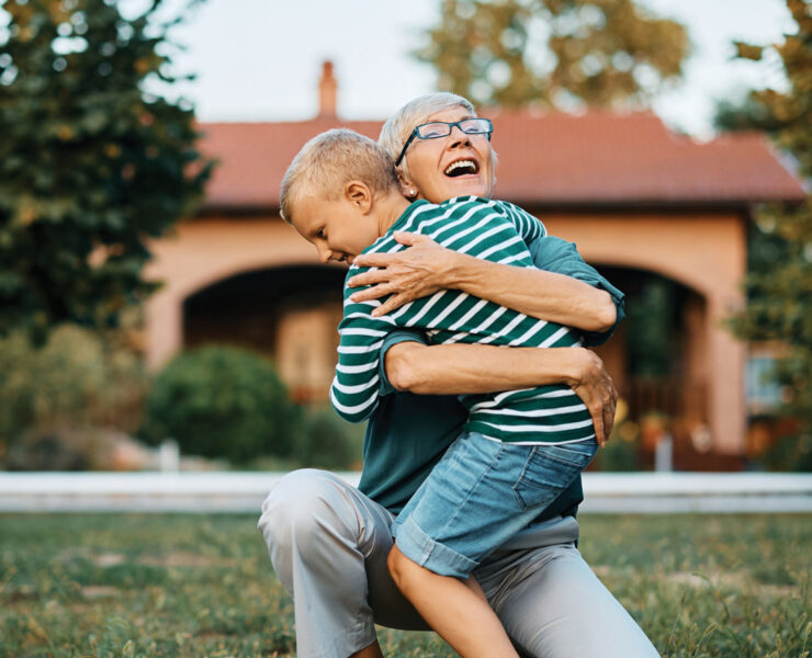 Older woman hugging young child in a yard