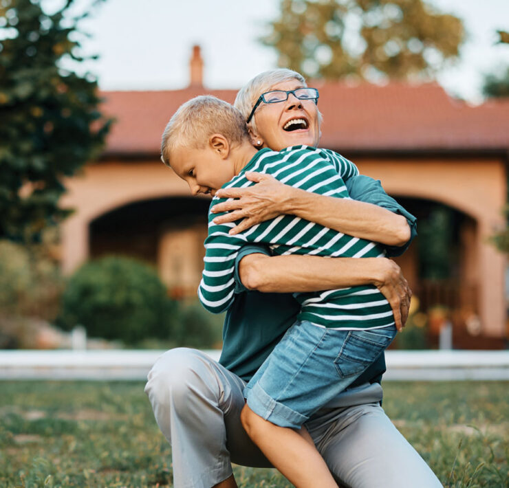 Older woman hugging young child in a yard