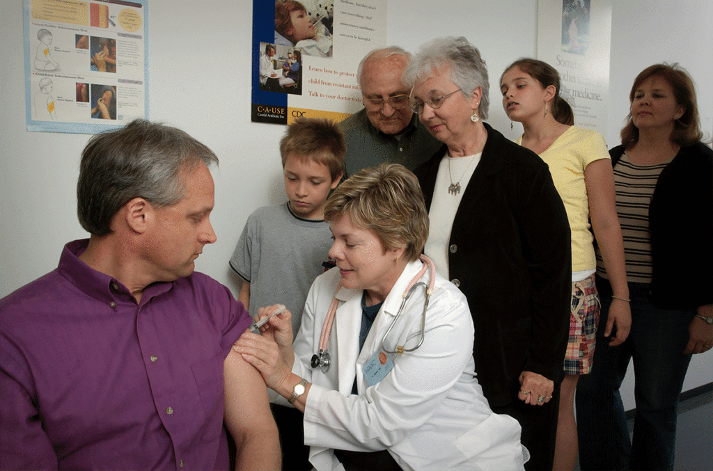 Unsplash photo from the CDC illustrating vaccine administration by a doctor in a white lab coat