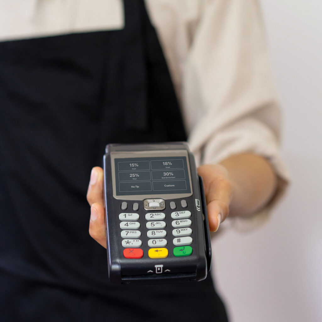 Server in apron holding a card reader.