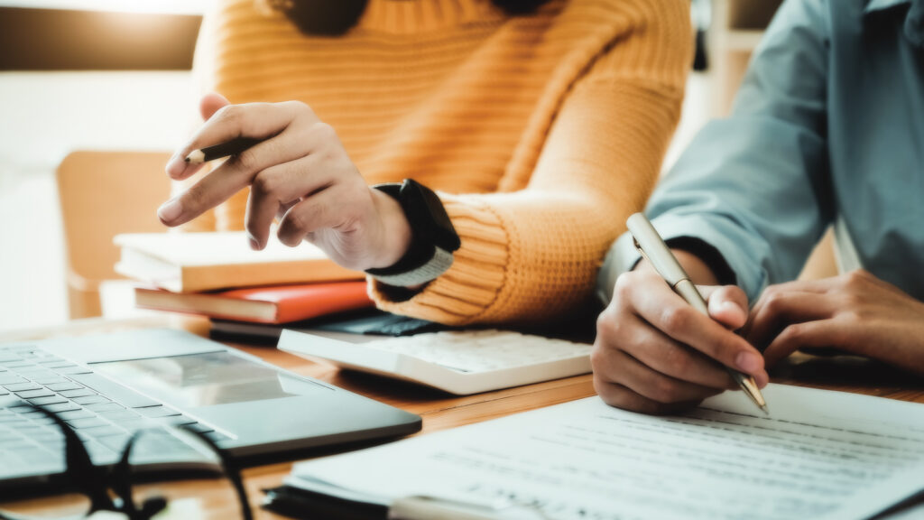 Two people hands holding pens and discussing A Budget contract