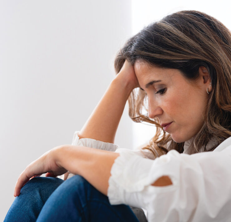 A Woman In A White Blouse Sitting And Resting holding her head