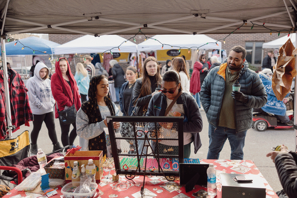 People shopping at a tent at the City Of Refuge Holiday Market.