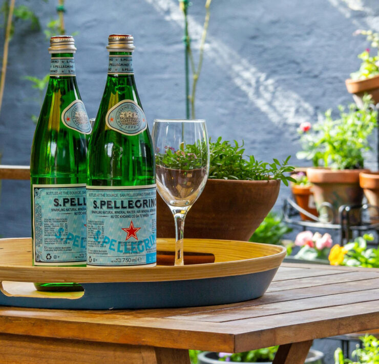 Featured Sparkling Water Sitting On A Table on an outdoor patio with flower pots in the background