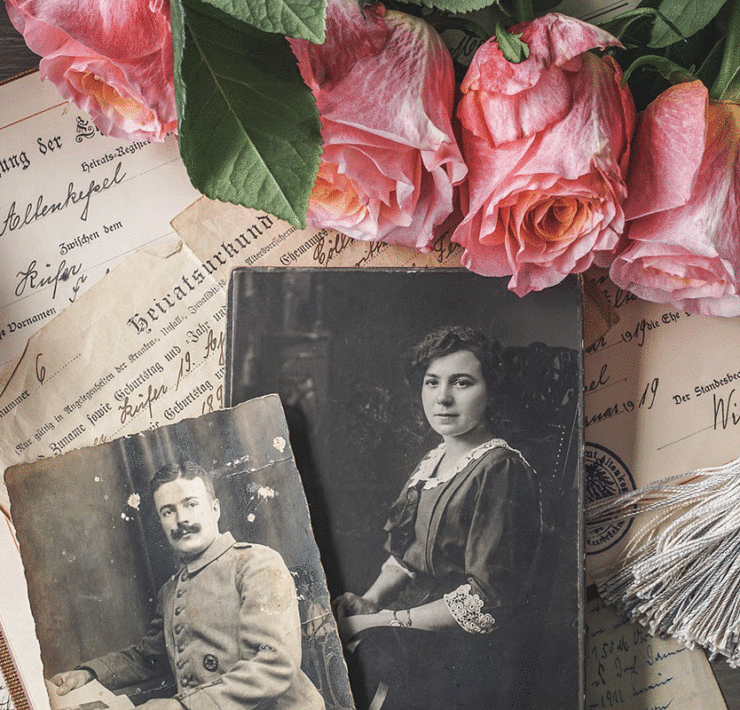 Recollection Agency Stock Feature a collection of vintage portraits and old documents next to a few roses