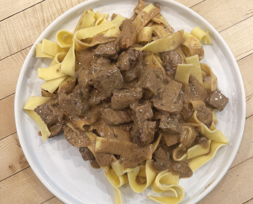 A Plate Of Prepared Beef Stroganoff Over Egg Noodles