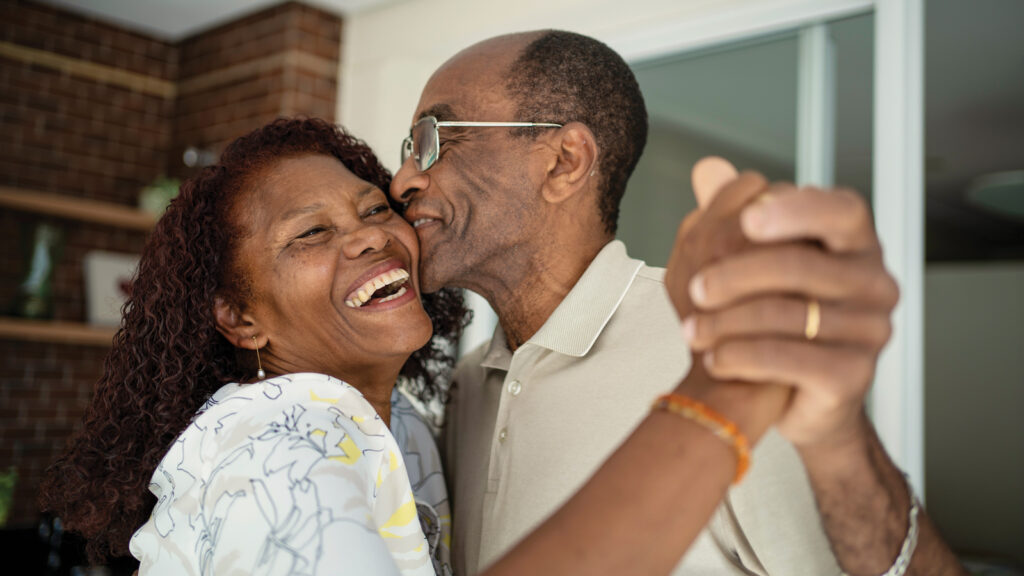 Older Couple Embrace With Smiles On Their Faces