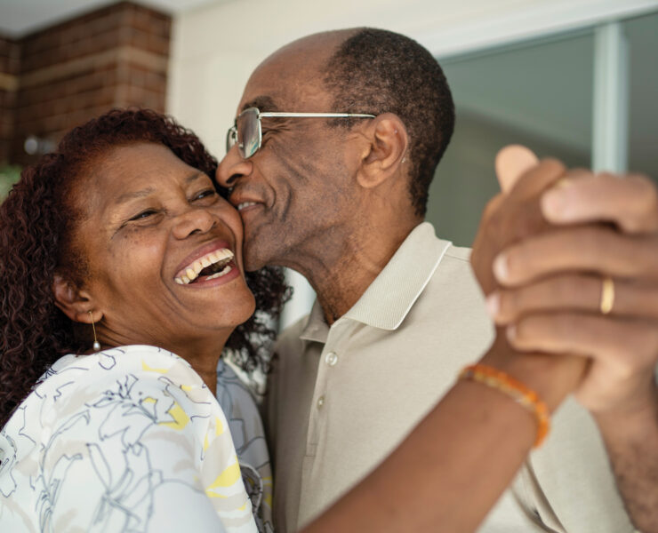 Older Couple Embrace With Smiles On Their Faces