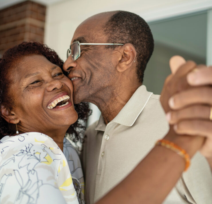 Older Couple Embrace With Smiles On Their Faces