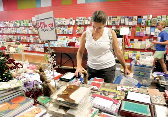 Kris Bezenek fills bins with discounted products while owner Veronica Kramer rushes around during the going-out-of business sale.