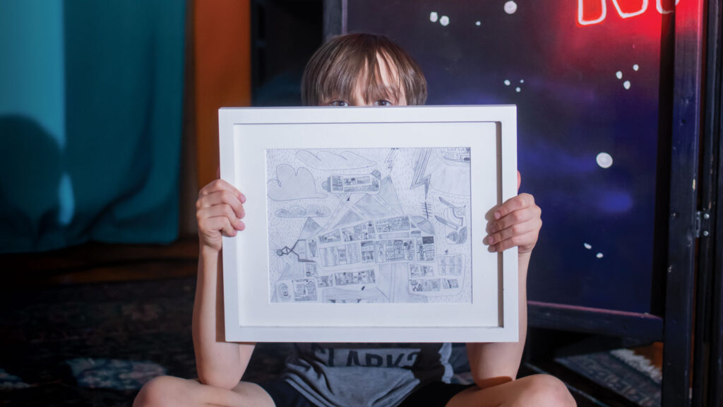 Featured Charlie Bittle Holding His Artwork On Stage At Cafe Berlin