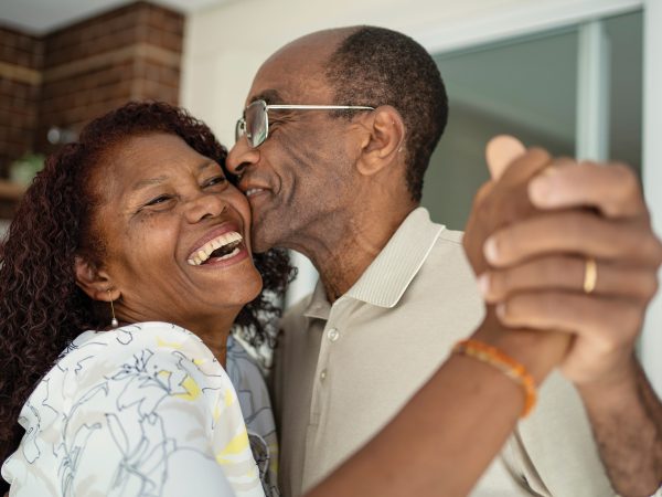 Older Couple Embrace With Smiles On Their Faces