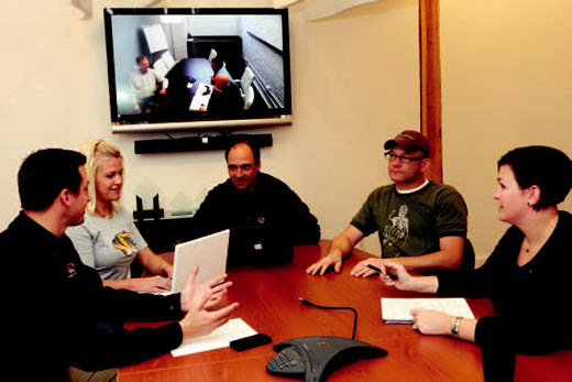 Woodruff, middle, goes over the logistics of an upcoming commercial shoot with his colleagues in the Columbia office while video conferencing with the Kansas City office as well.