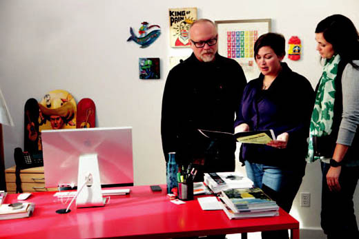 Sweitzer, left, converses with employees on a creative project in his office. Sweitzer, left, converses with employees on a creative project in his office.