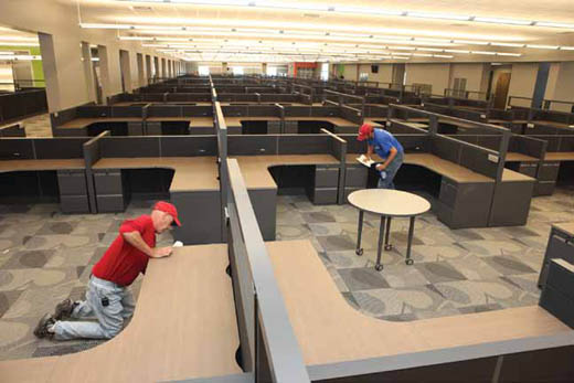 Doug Marting, left, of Team Ofice puts the inishing touches on one of the desks at IBM's center.