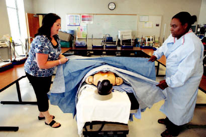 Carrie Golightly, left, demonstrates draping with her student Ashontai Spruell. Golightly prepares about 20 students a year for a career in surgical technology through the Columbia Area Career Center's surgical technology program.