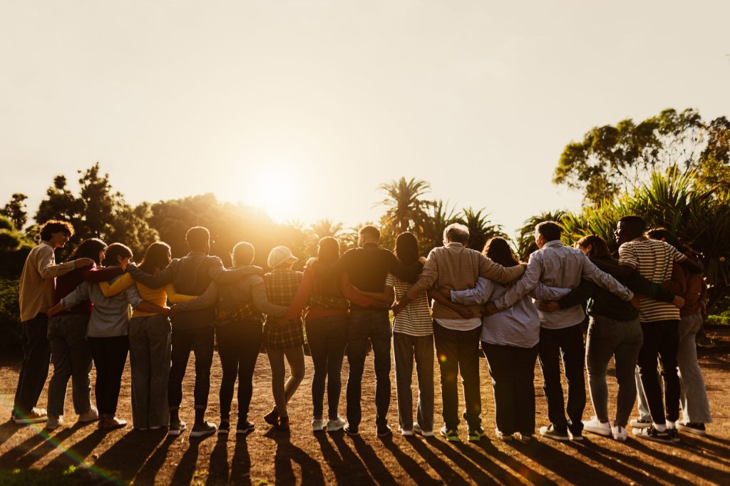 Back View Of Happy Multigenerational People Having Fun In A Public Park During Sunset Time Community And Support Concept