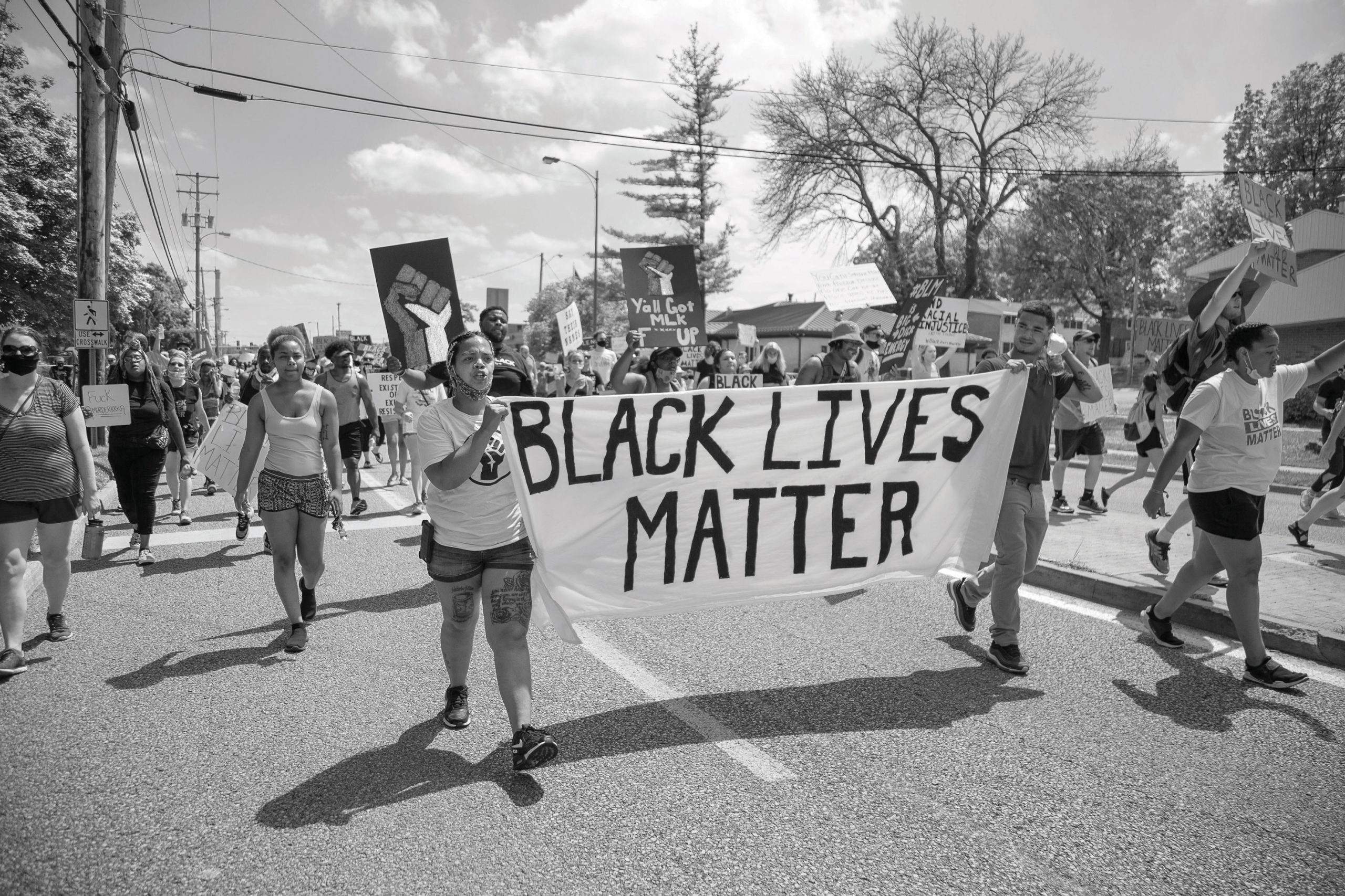 Black-Lives-Matter-Protest-two-black-women-carry-a-sign-saying-Black-Lives-Matter-hundreds-of-people-march-around-them