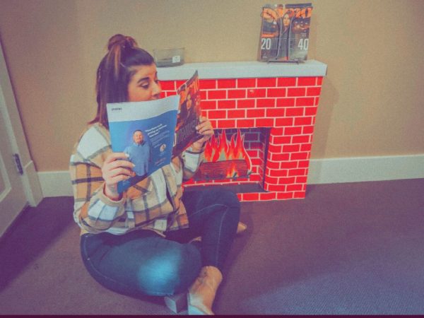 A women reads the Como magazine in front of a fake fireplace