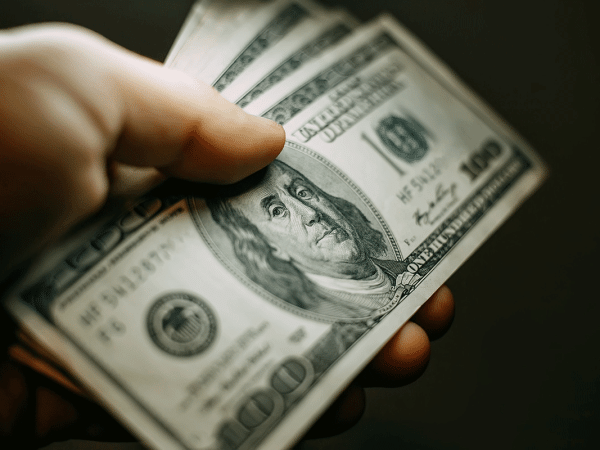 hand holding several $100 bills