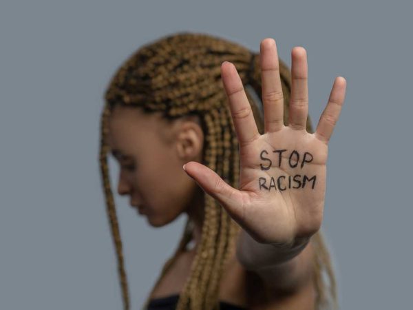 Gettyimages women holding up her hand which has the written words Stop Racism