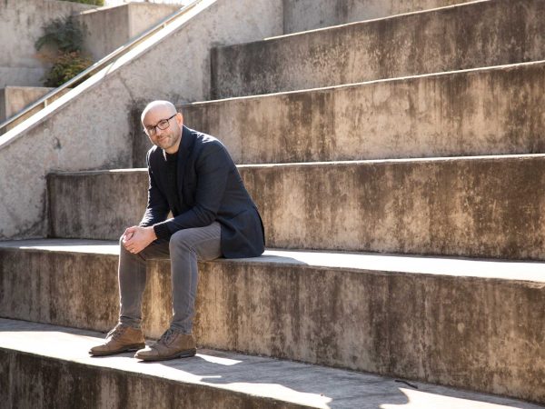 Headshot of a man named Robert Greene sitting on concrete steps