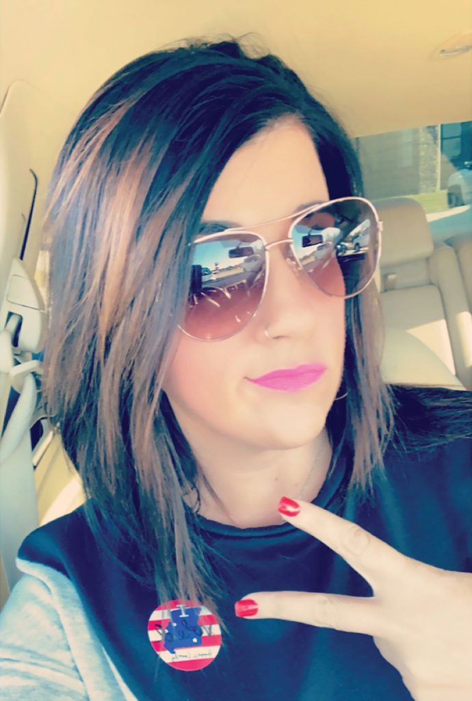 A women in a vehicle poses with her "I voted" sticker