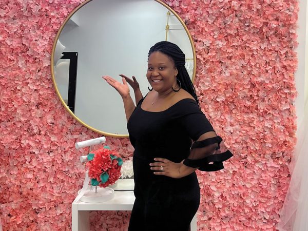 Stars Simmons poses alongside a rack of bridal gowns