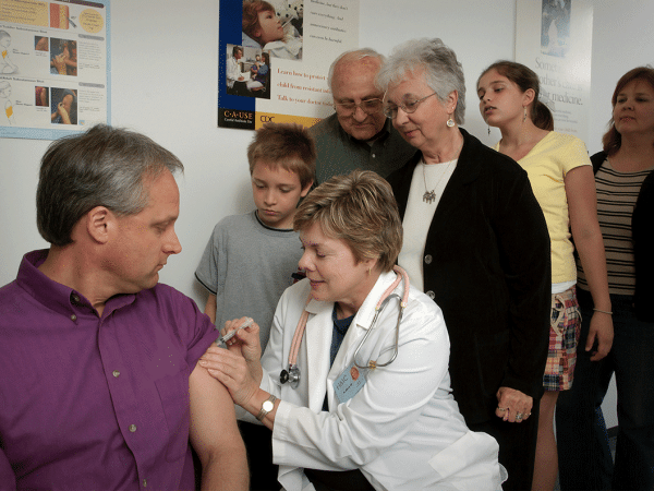 Unsplash photo from the CDC illustrating vaccine administration by a doctor in a white lab coat