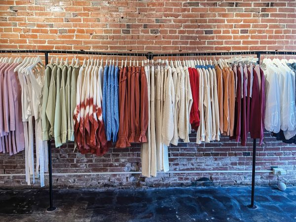 a rack of full clothes against a exposed brick wall