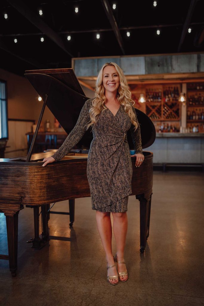 Headshot of a women named Amanda Ruyle standing in front of a piano