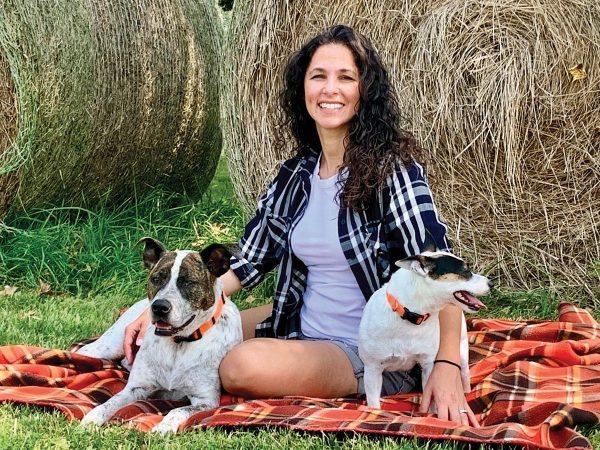Angie Randazzo of Paws In Heaven with her two dogs outside on a blanket