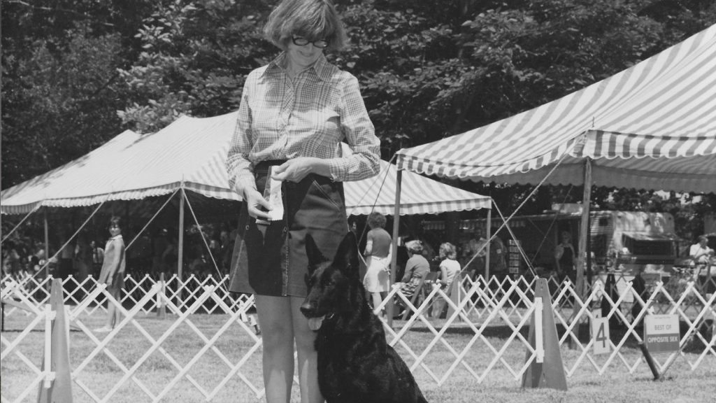 with people gathered in the background. The photo is in black and white.