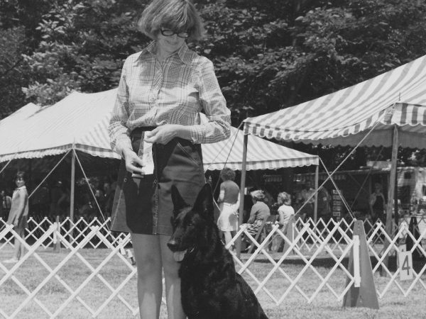 with people gathered in the background. The photo is in black and white.