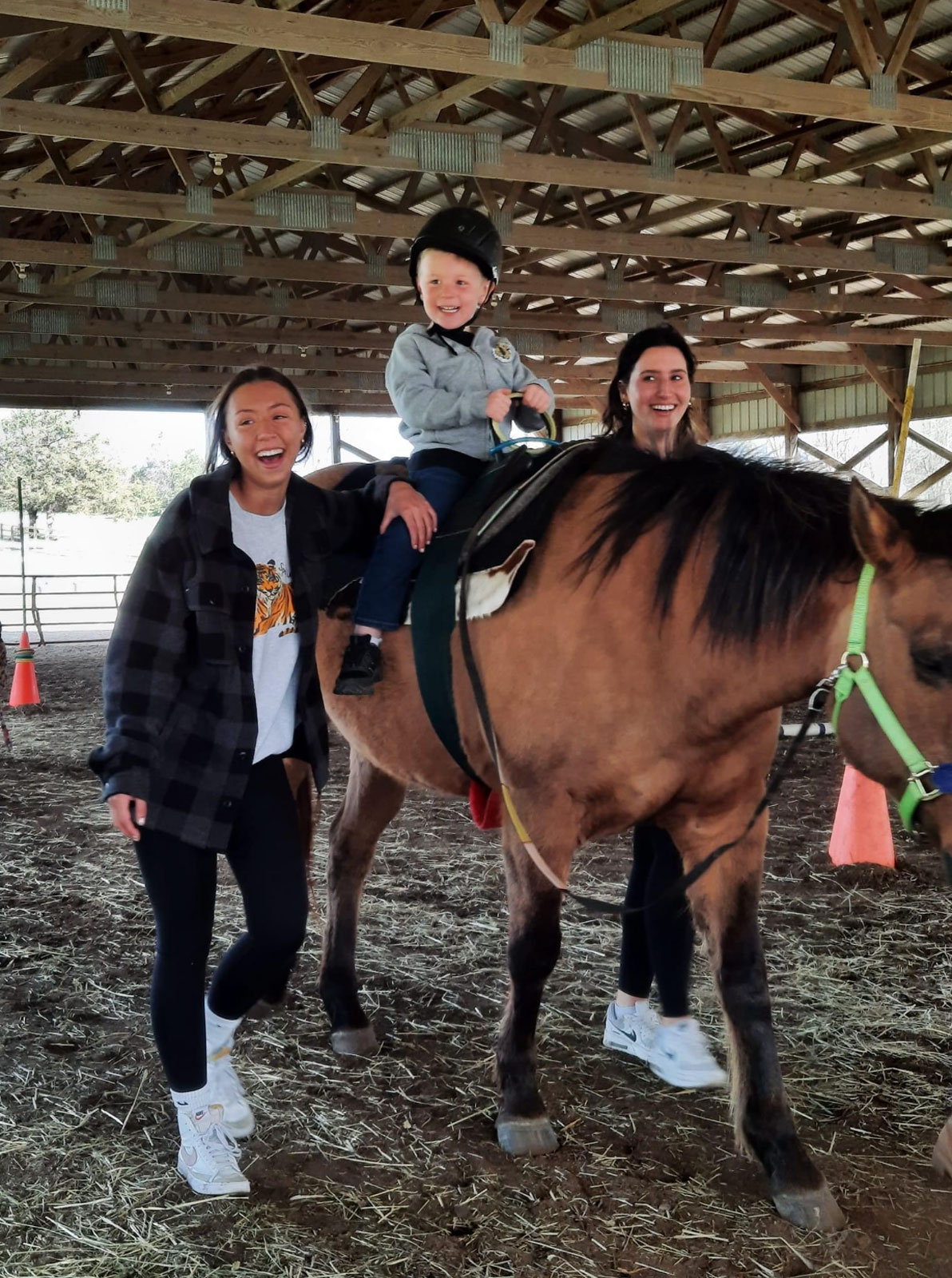 A happy group smiling big while a young rider rides a horse at Cedar Creek.