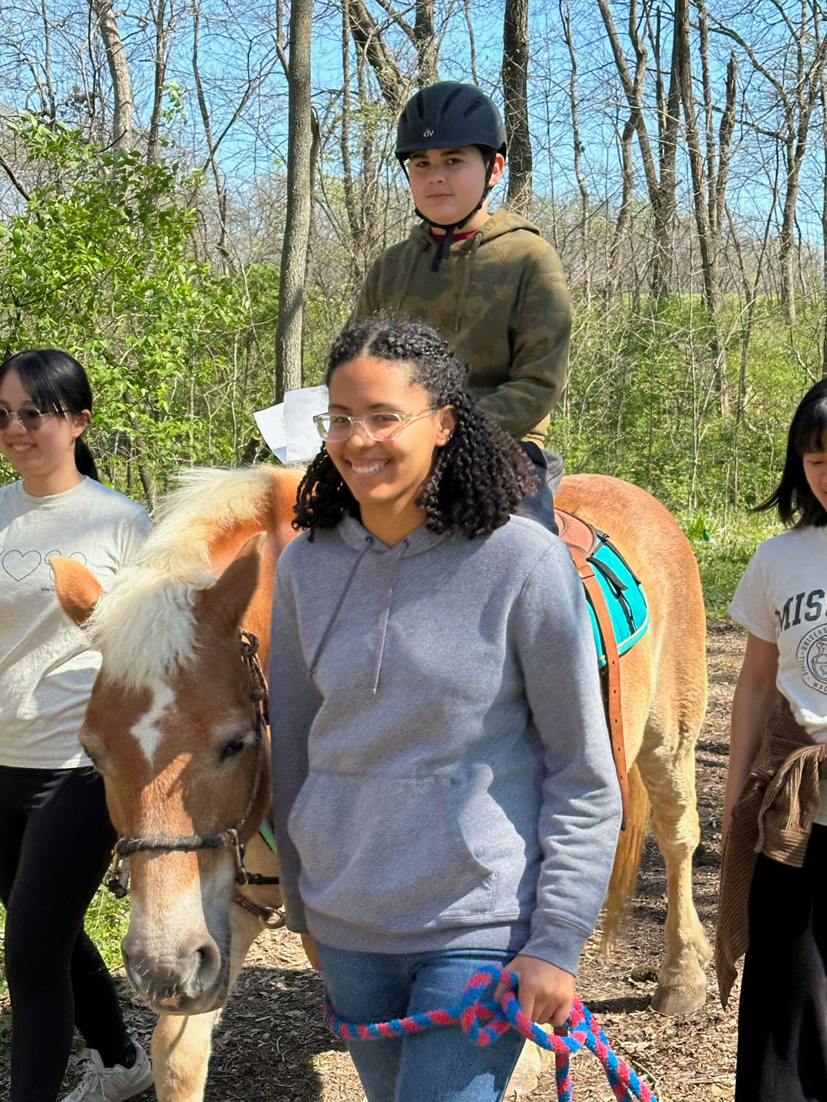 A smiling group walking a young rider on his horse at Cedar Creek.